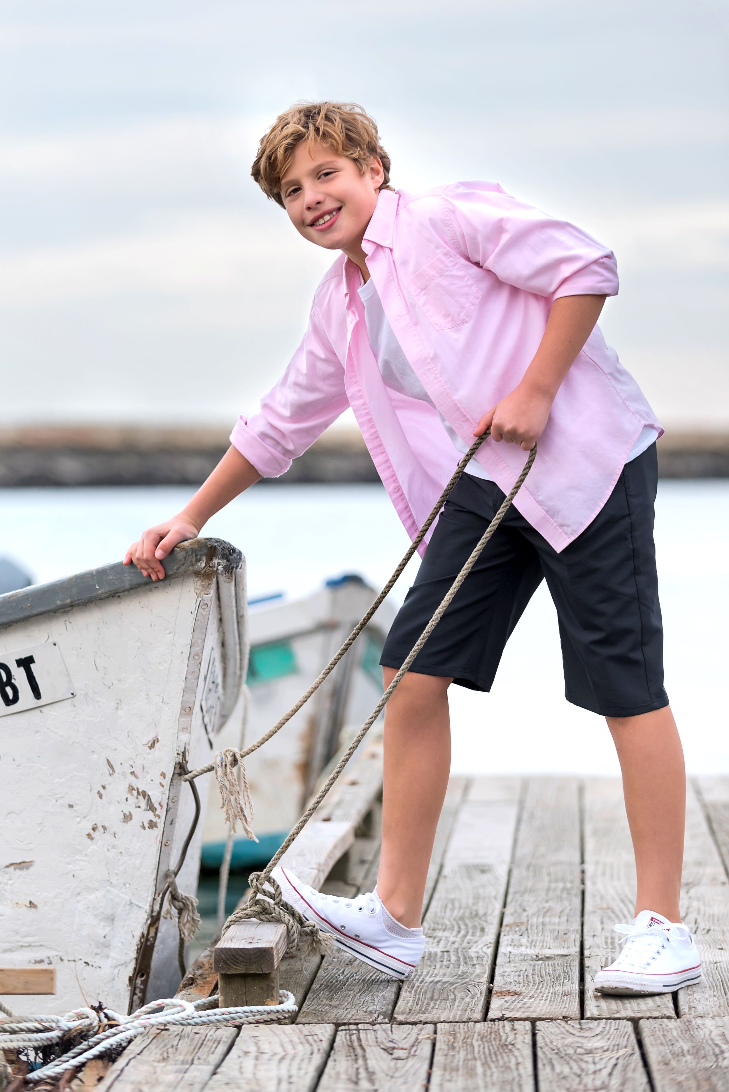 Tween male model wearing preppy clothes on the dock