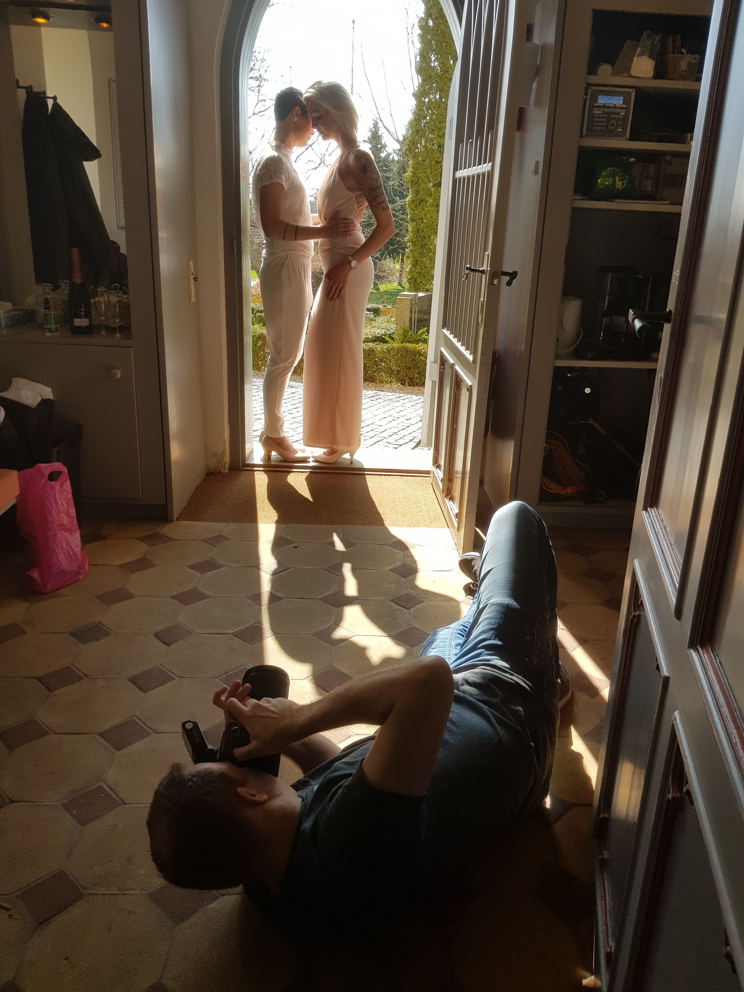Fotograf ligger på gulvet og tager billede af brudepar i døråbning