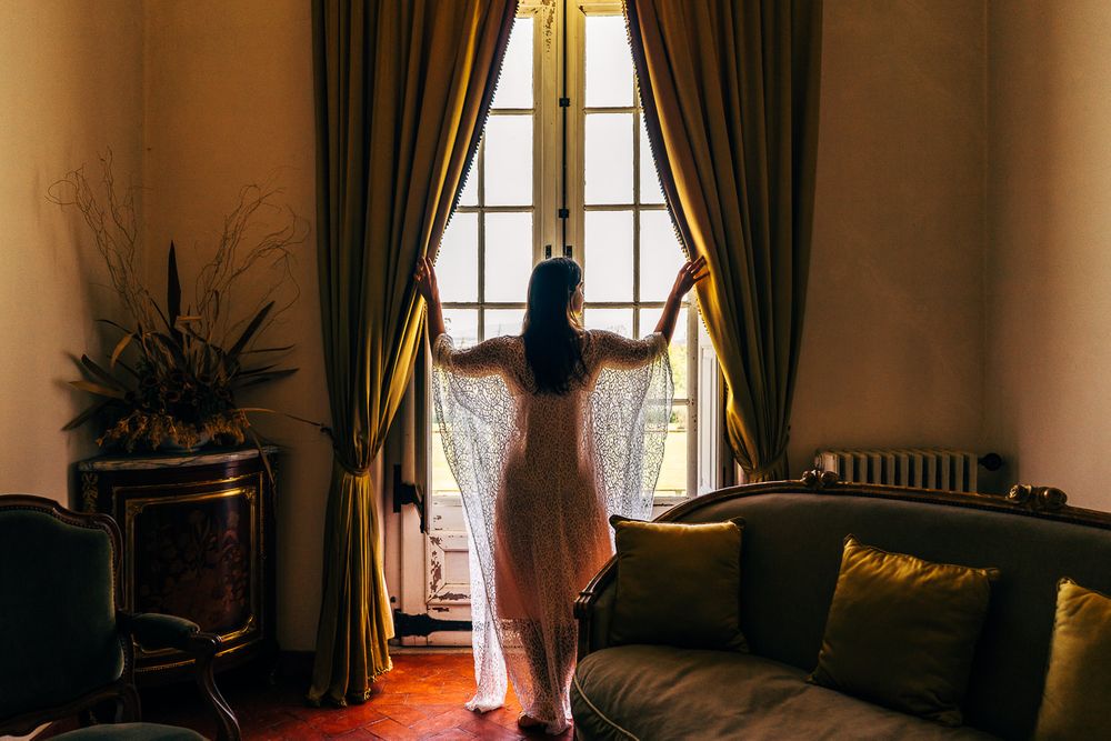 Noiva de robe, com os dois braços a abrir o cortinado do palácio de são marcos, Coimbra.