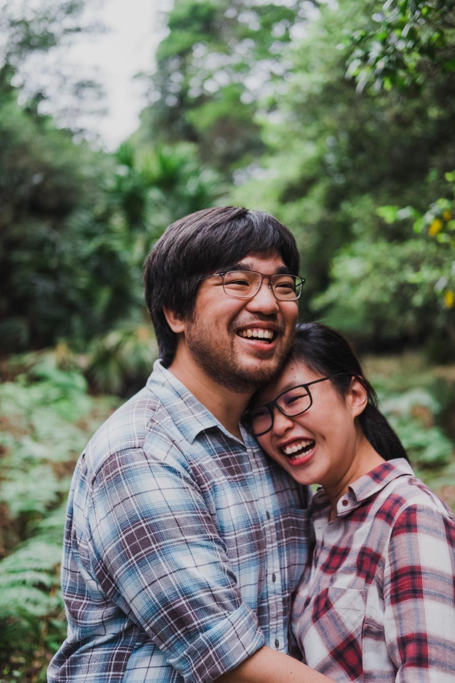Couple laughing as they hold each other in the forest