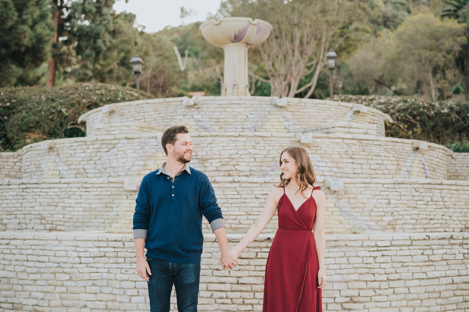 couple holding hands in front of stone fountain
