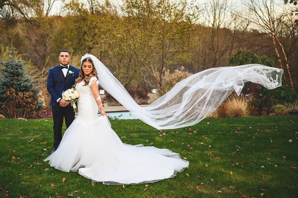 bride and groom portrait with flying veil at stone house