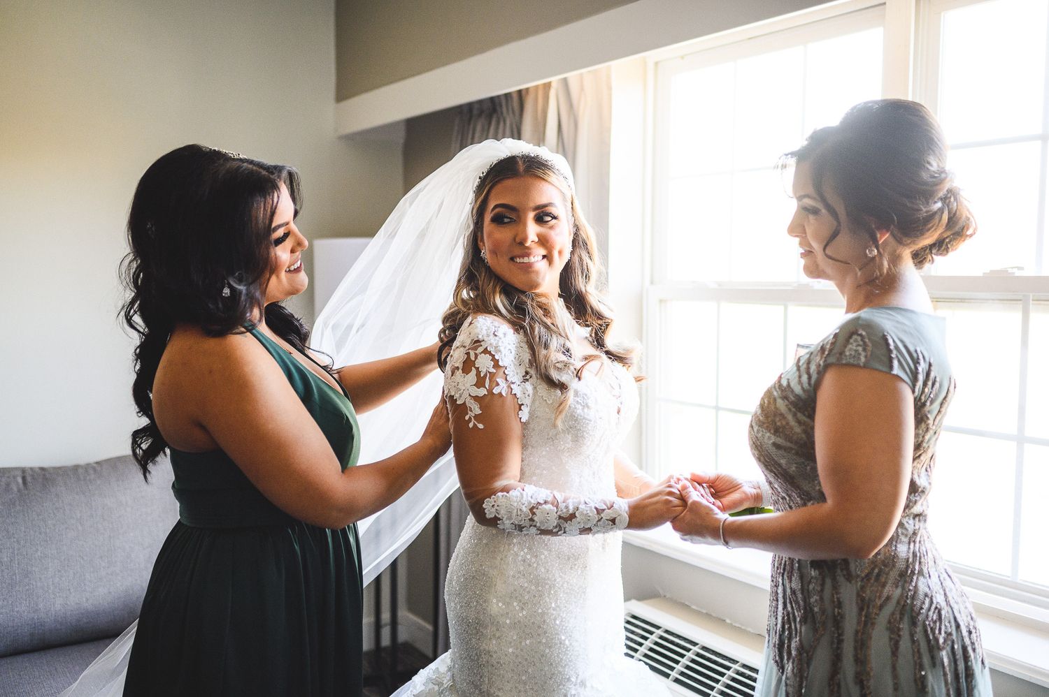 bride with mom and sister smiling during bride prep
