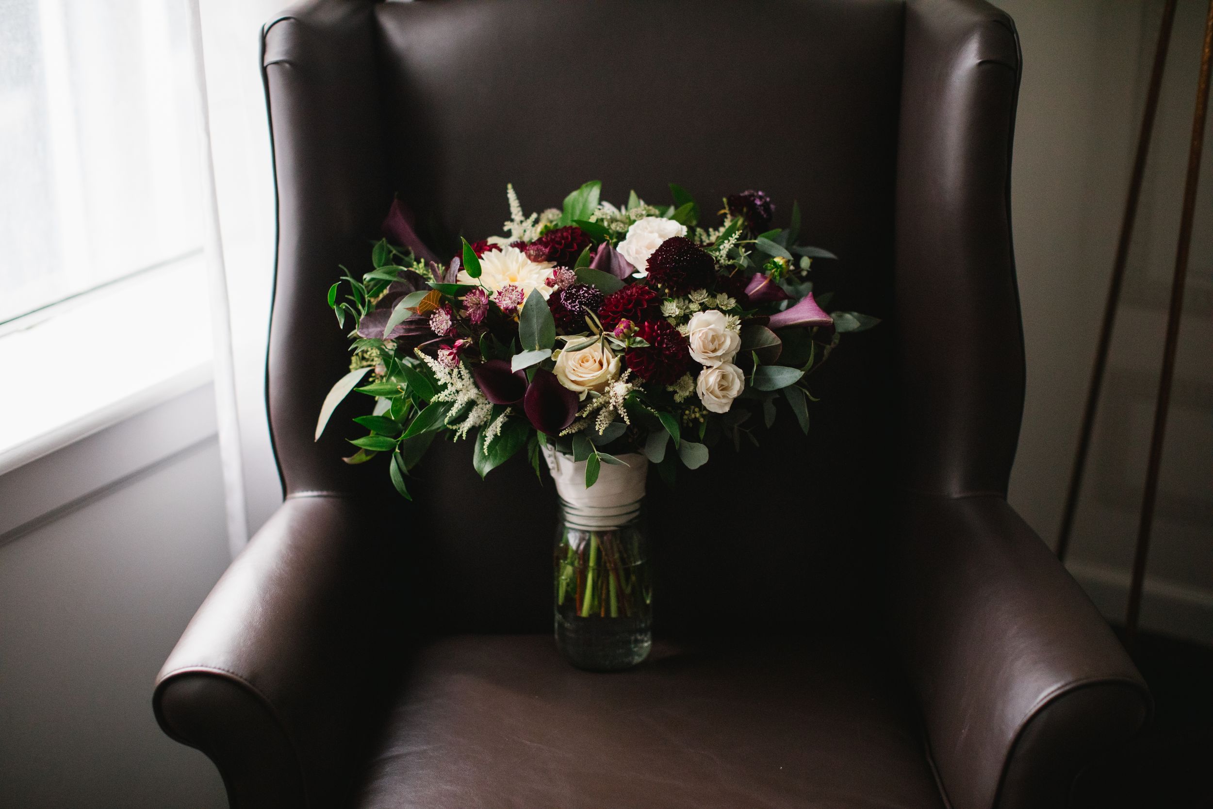 burgundy bridal floral bouquet on brown leather armchair
