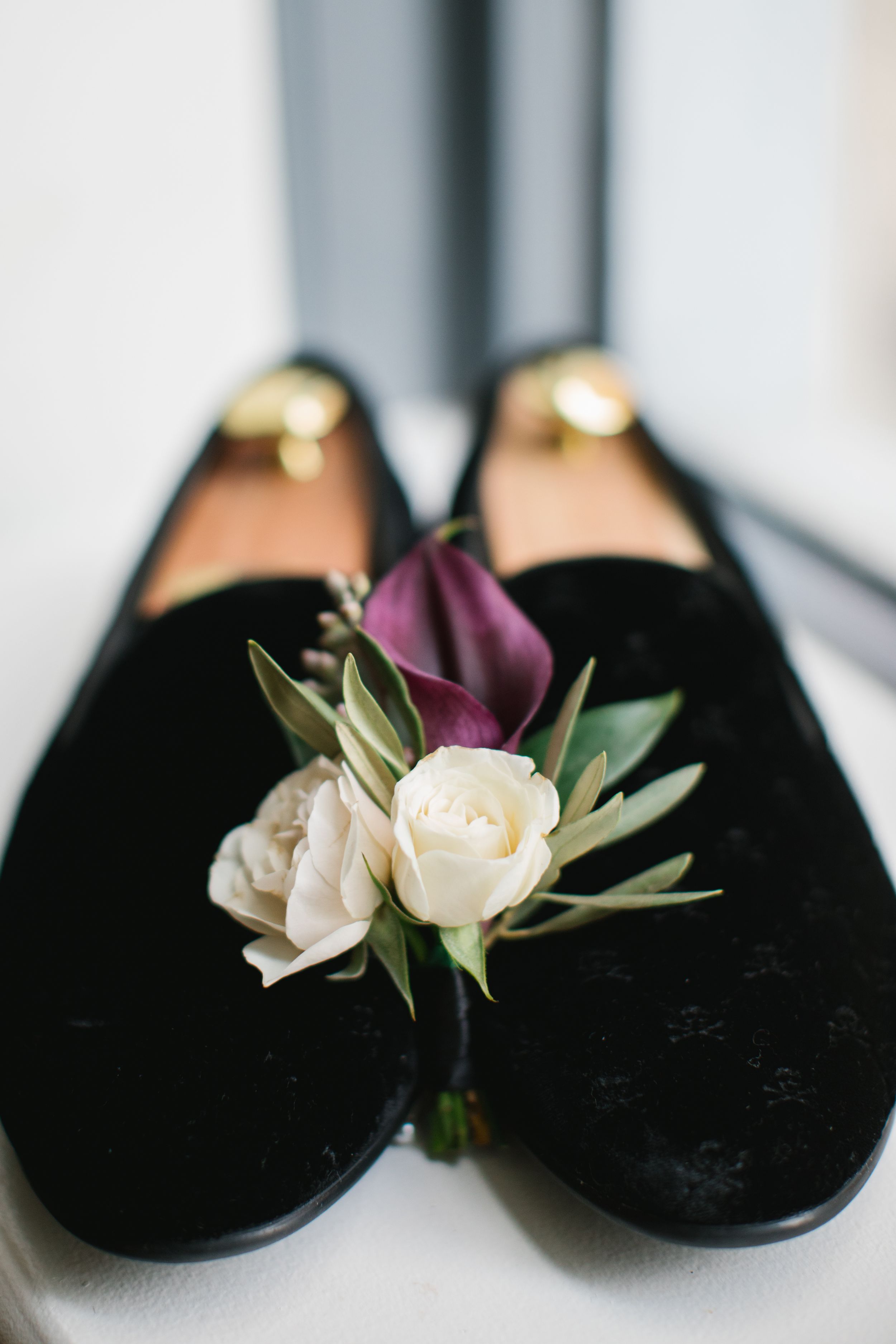 close up of grooms boutonniere between his tuxedo slippers