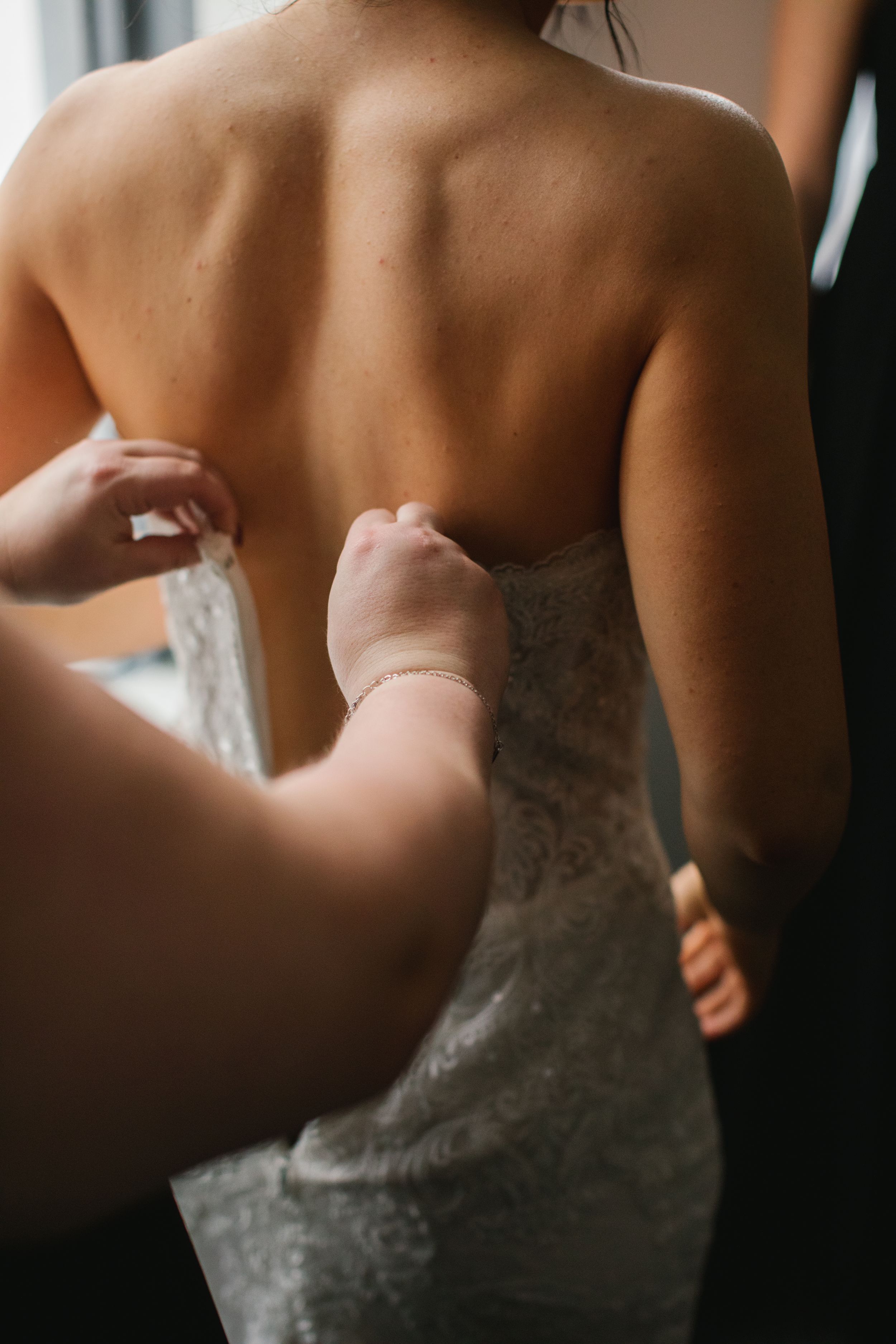 bridesmaid zipping up wedding dress from the back