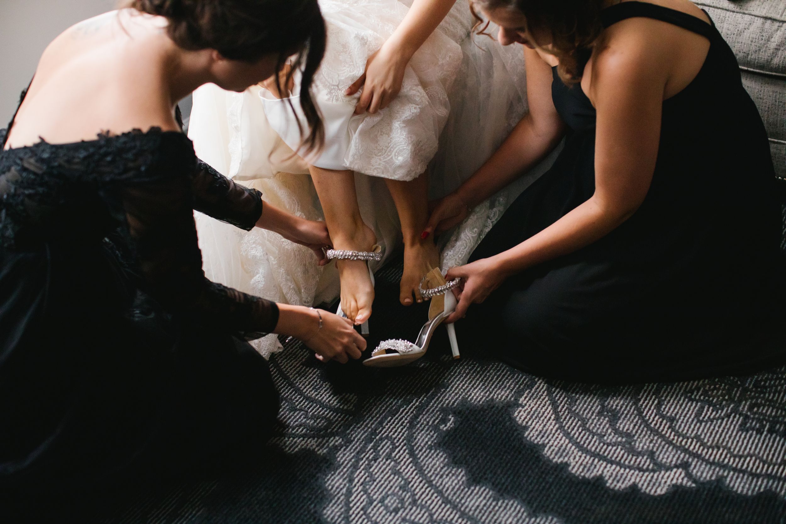 bridesmaids helping bride put on her shoes