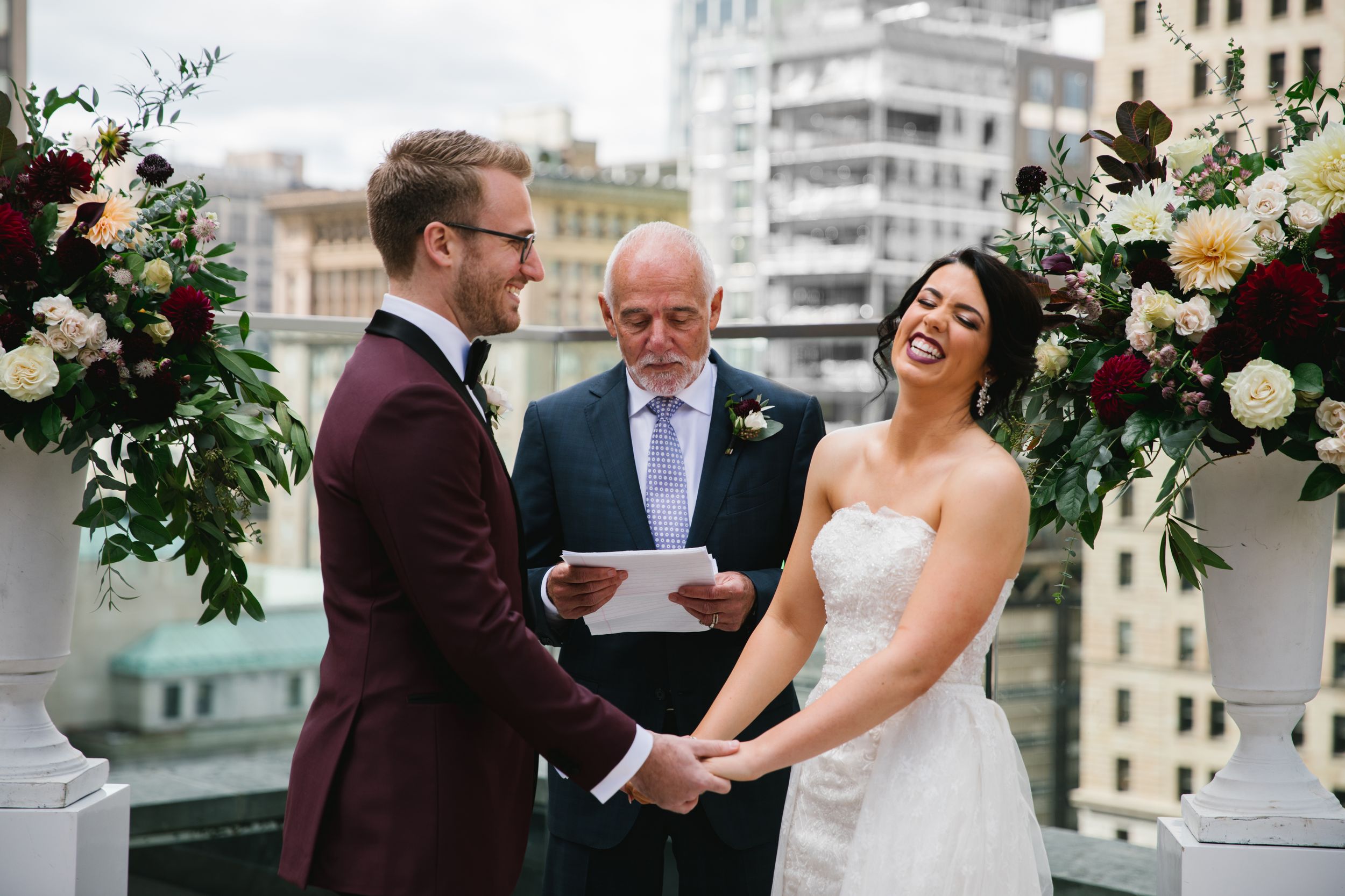 bride and groom holding hands during ceremony and laughing while officiant reads