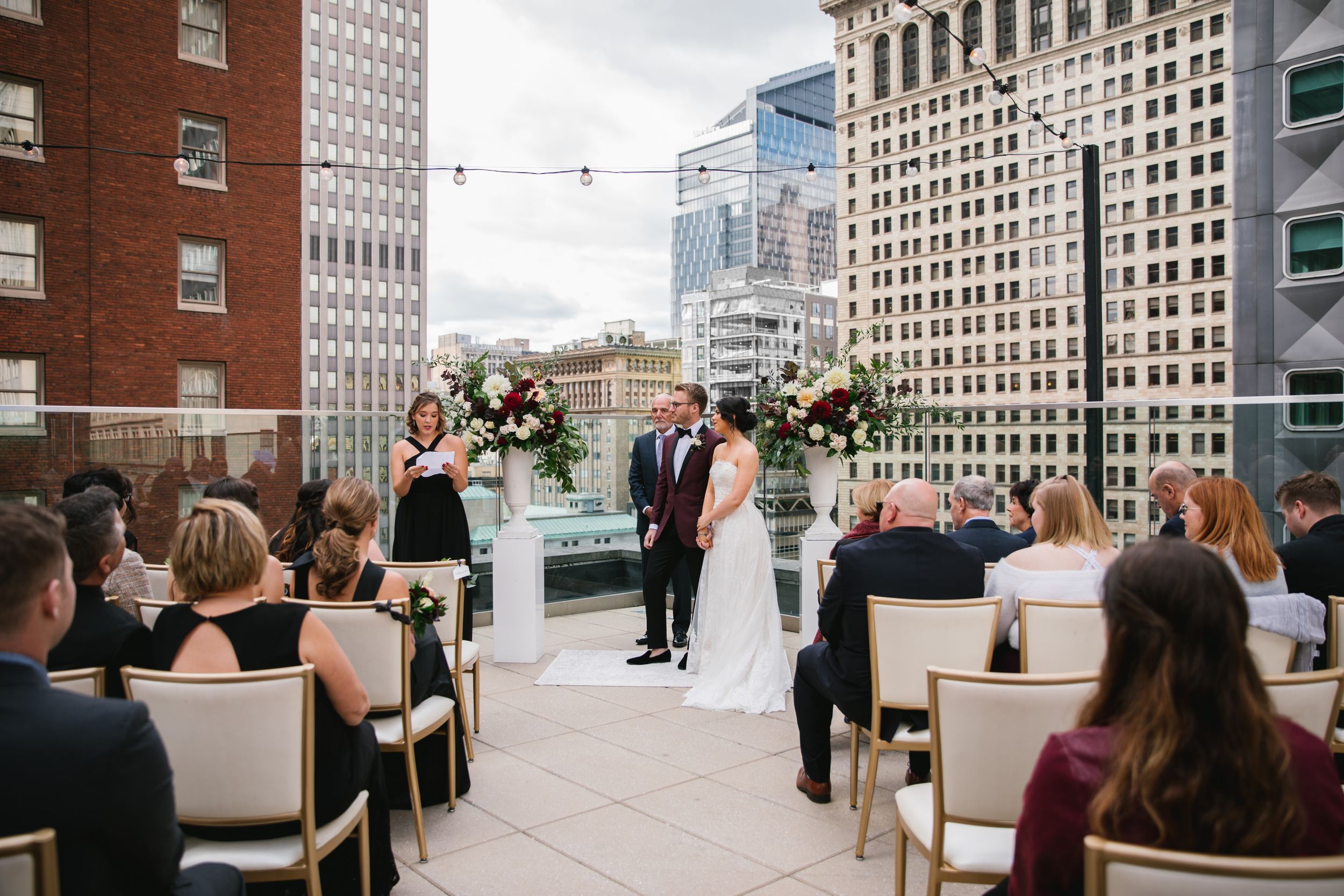 bridesmaid reads while bride and groom look on and hold hands during ceremony