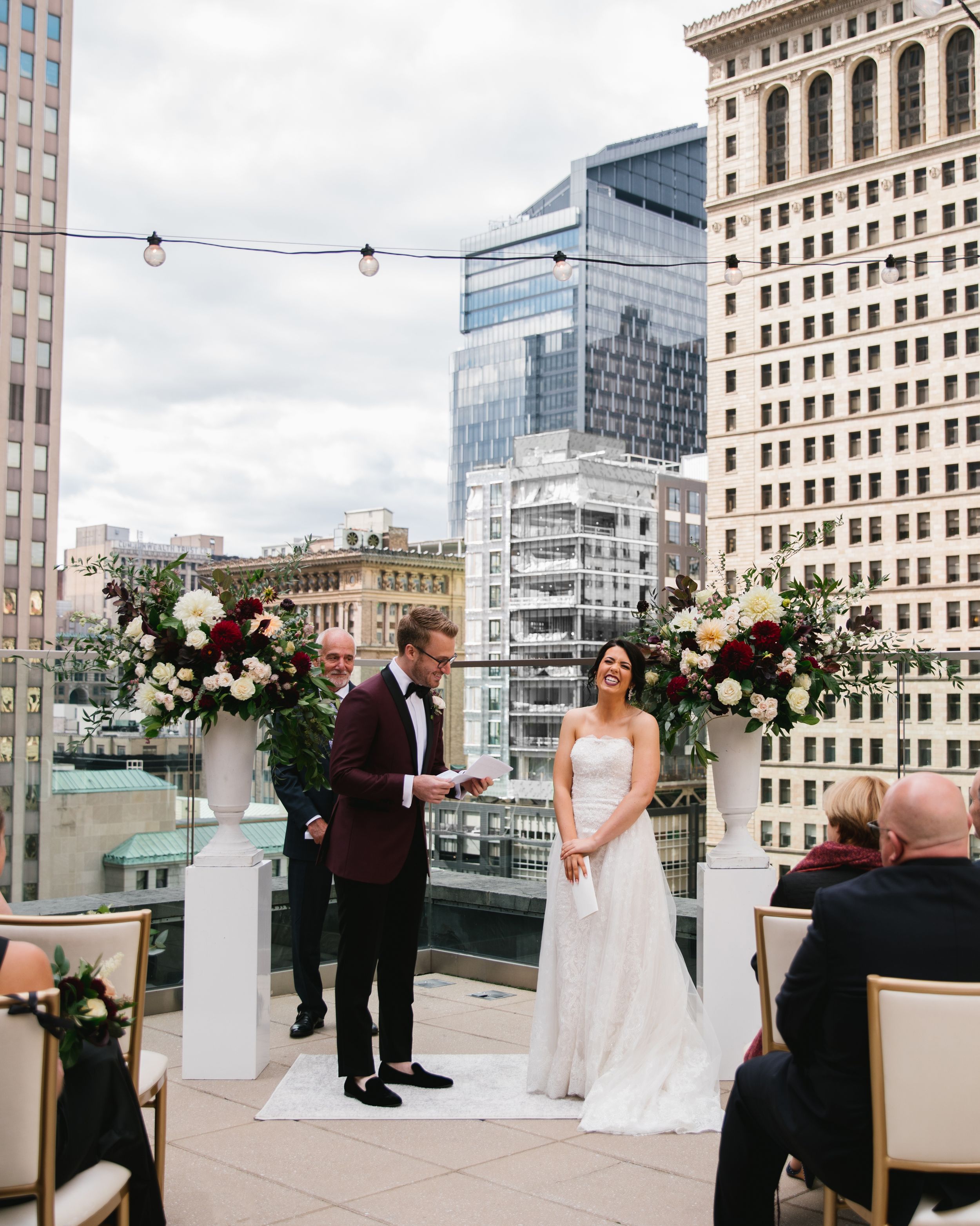 bride laughing while groom reads his vows at rooftop ceremony overlooking the city skyline toronto