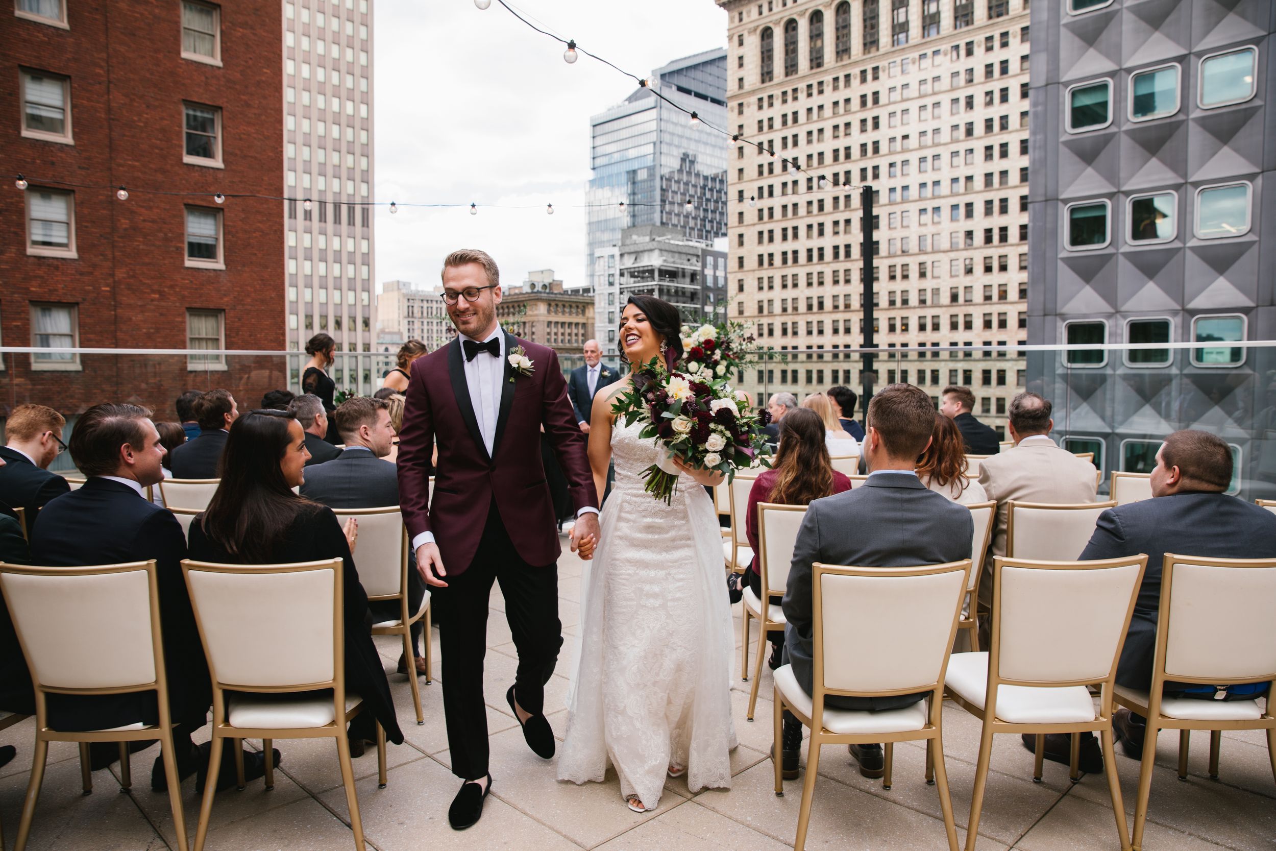 bride and groom walking down the aisle during rooftop ceremony laughing and holding hands
