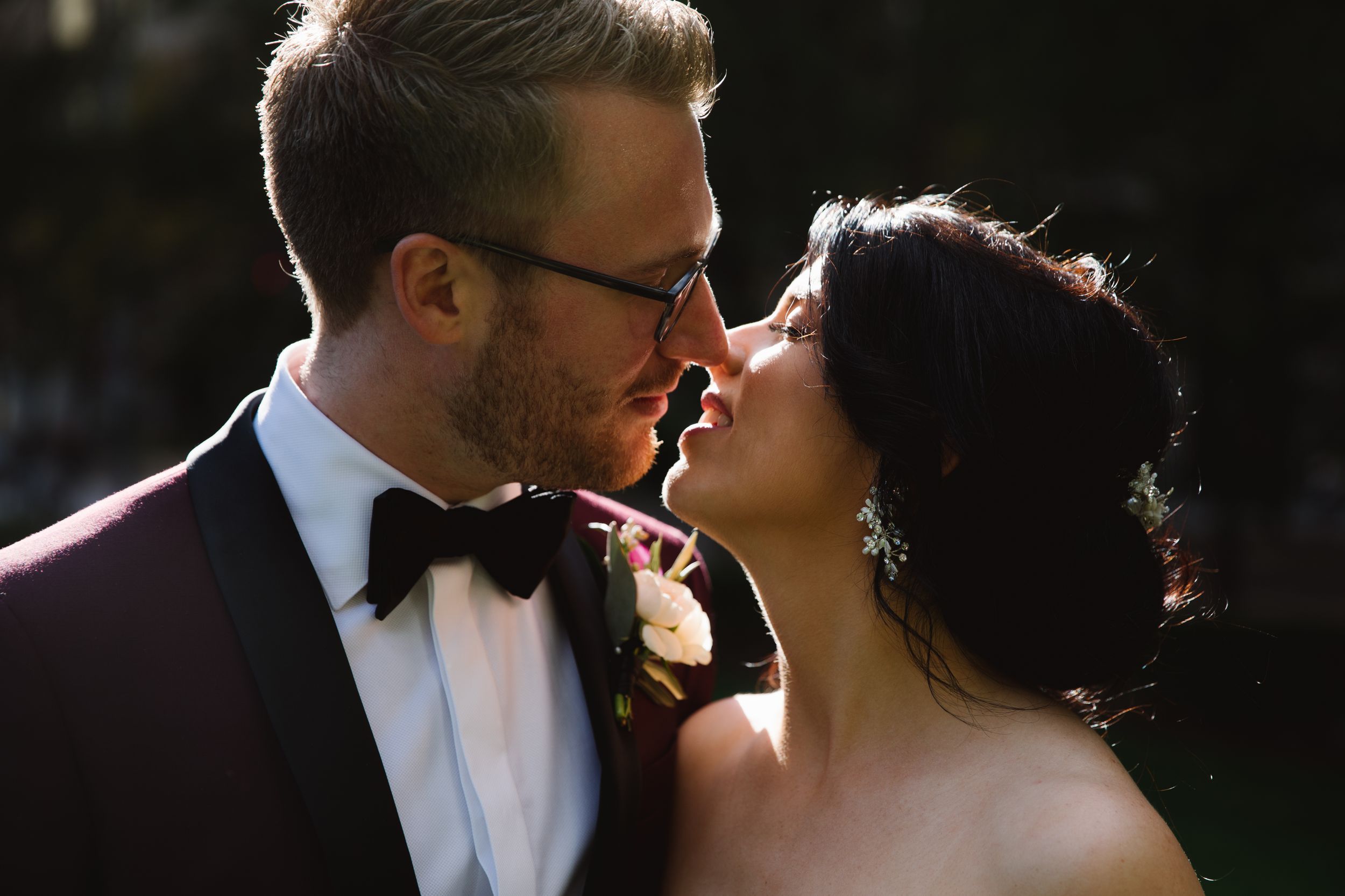 bride and groom kiss with sun shining on them