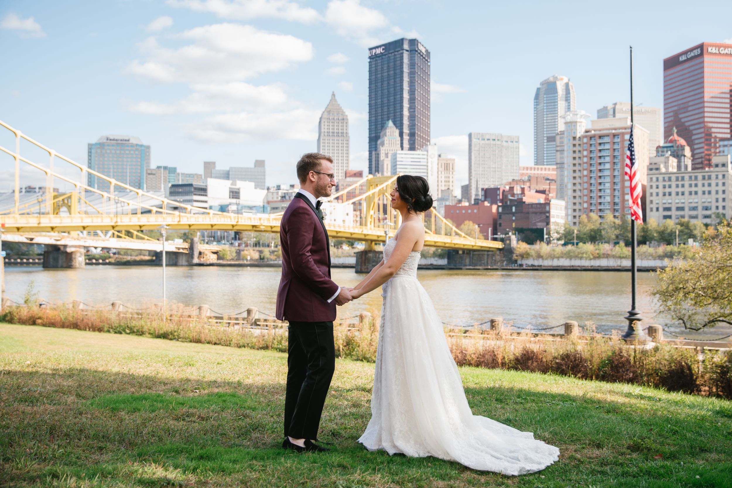 bride and groom holding hands with pittsburgh city behind them
