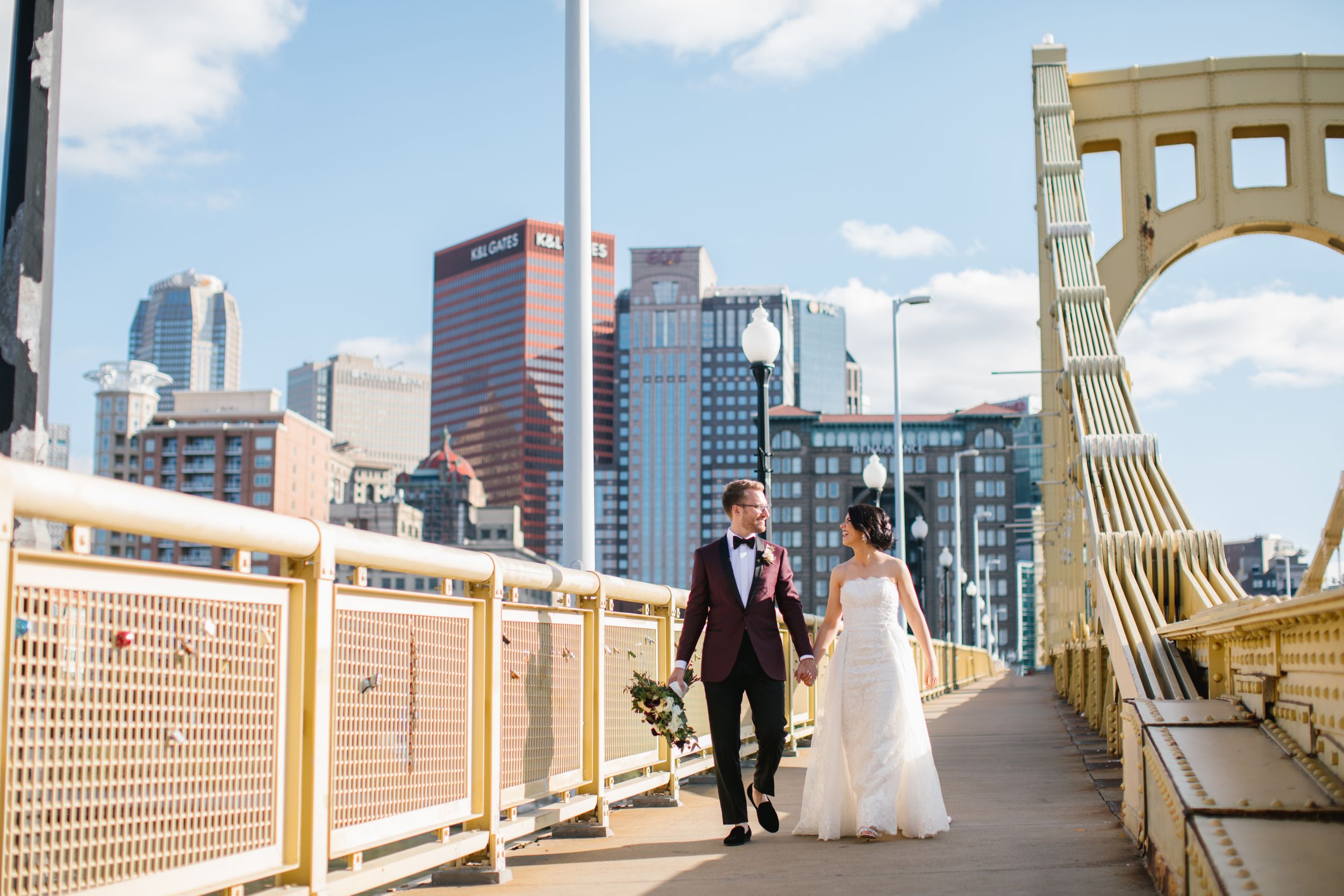 bride and groom walk on yellow bridge in pittsburgh city pennsylvania wedding