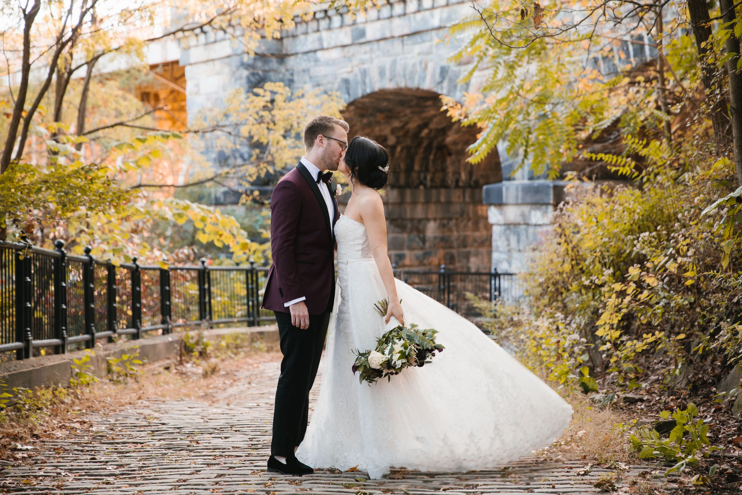 bride and groom kiss schenley park pittsburgh with bridge behind them and her dress is flying