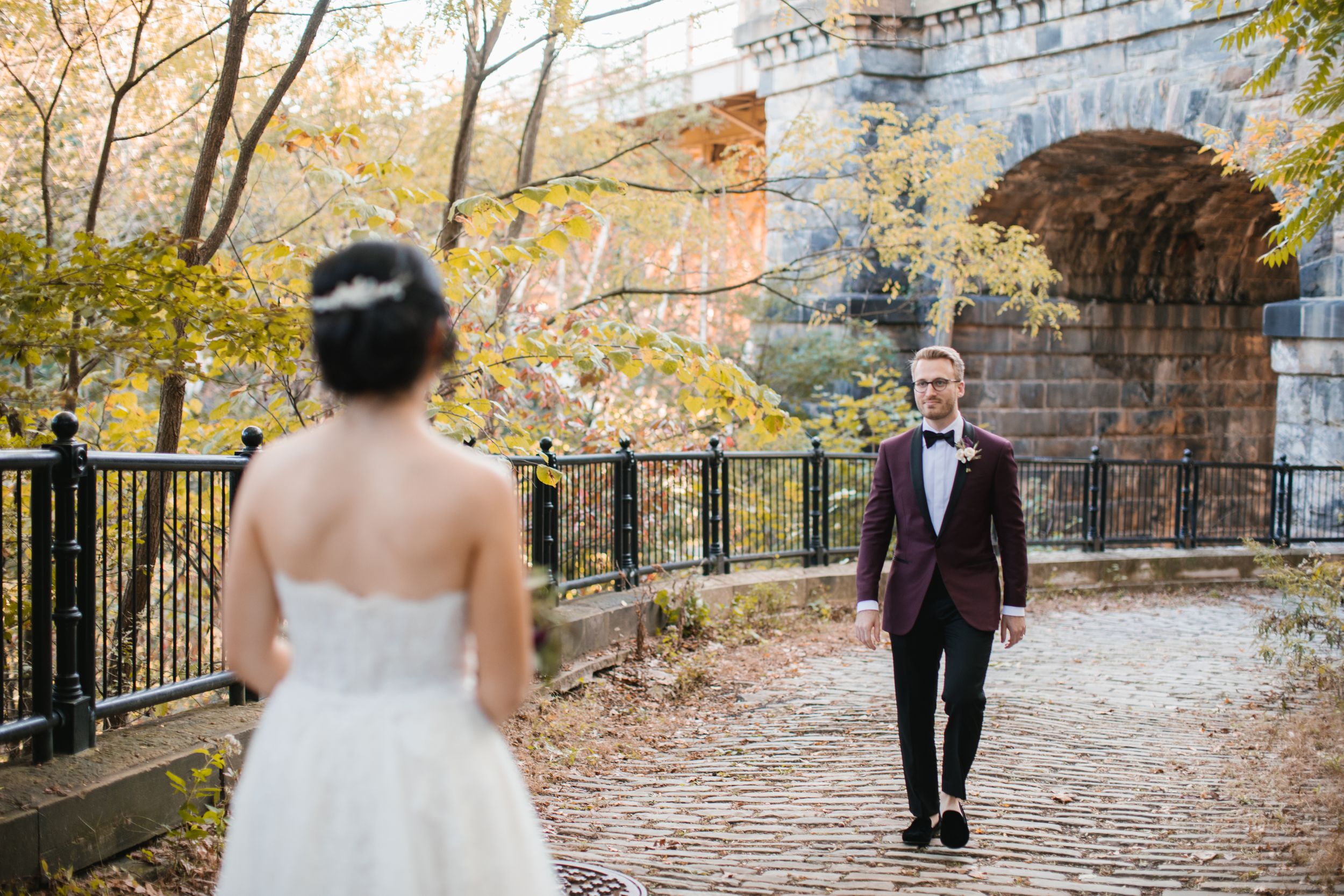 groom walking towards bride in park during fall