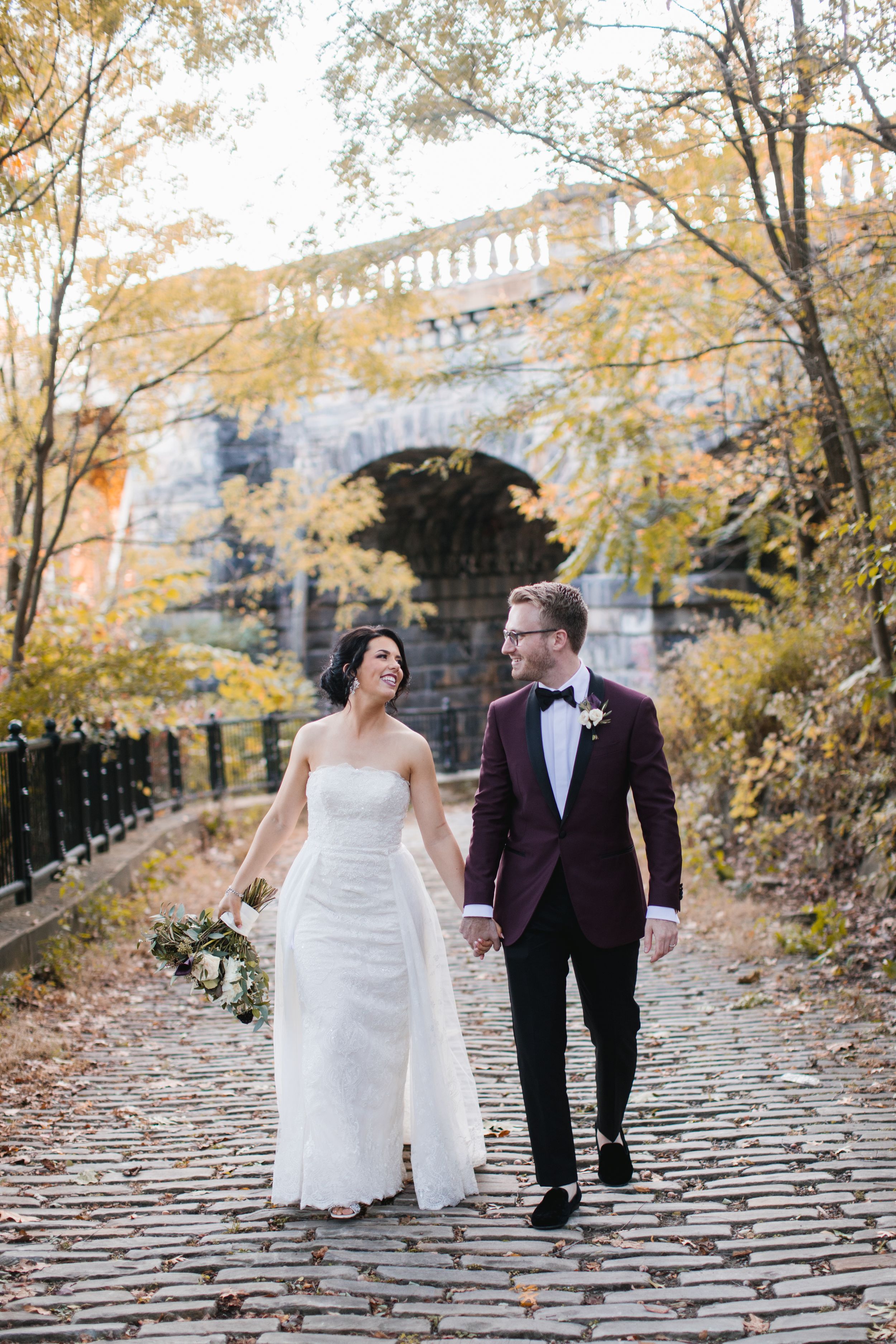 bride and groom holding hands and walking, laughing in park during fall toronto