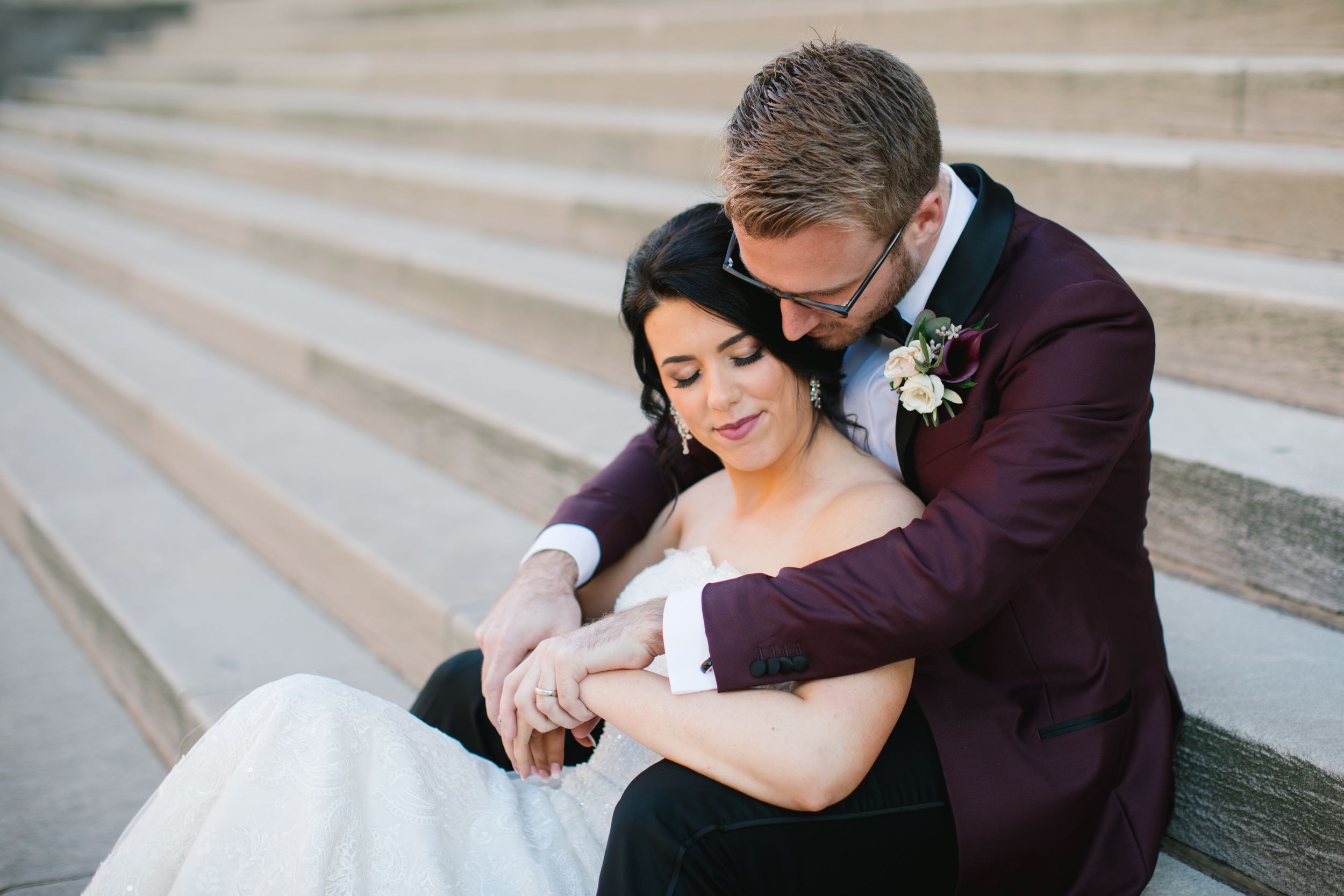 bride and groom hugging and sitting on concrete steps