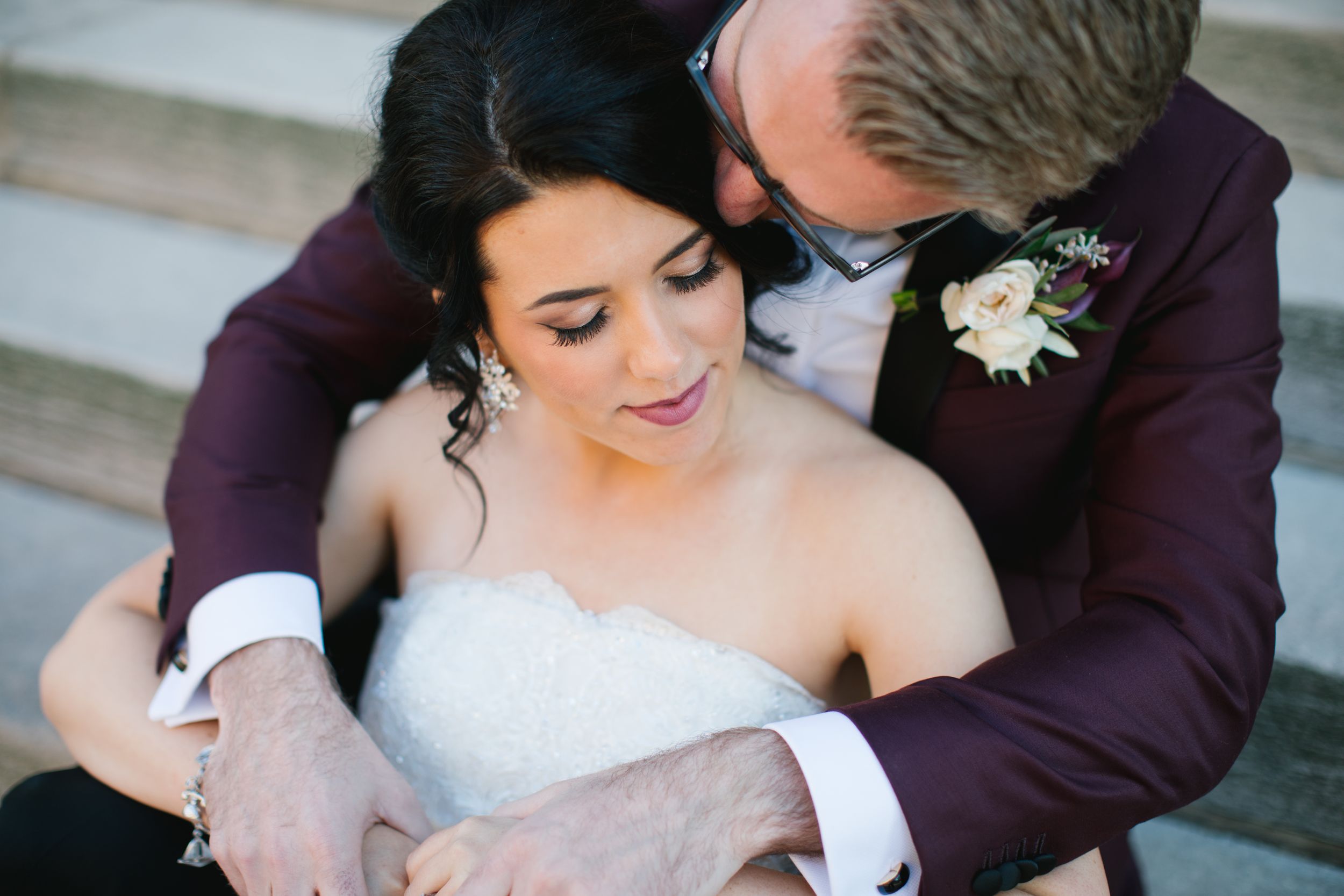 bride and groom hugging and sitting on concrete steps