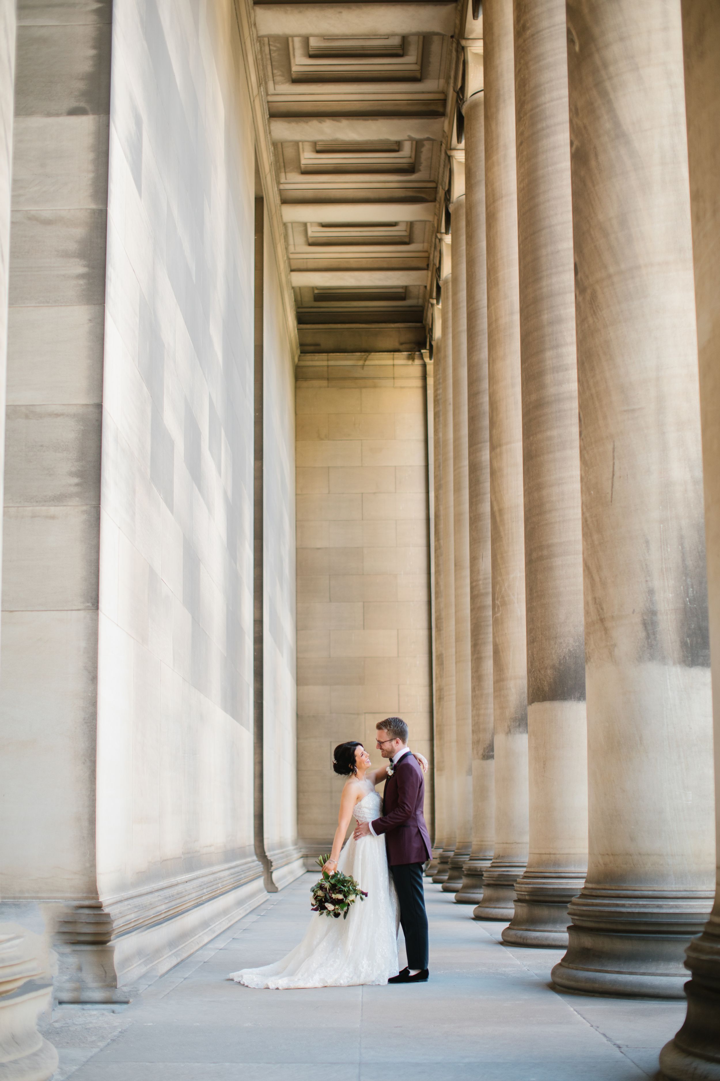 bride and groom with tall columns at a museum