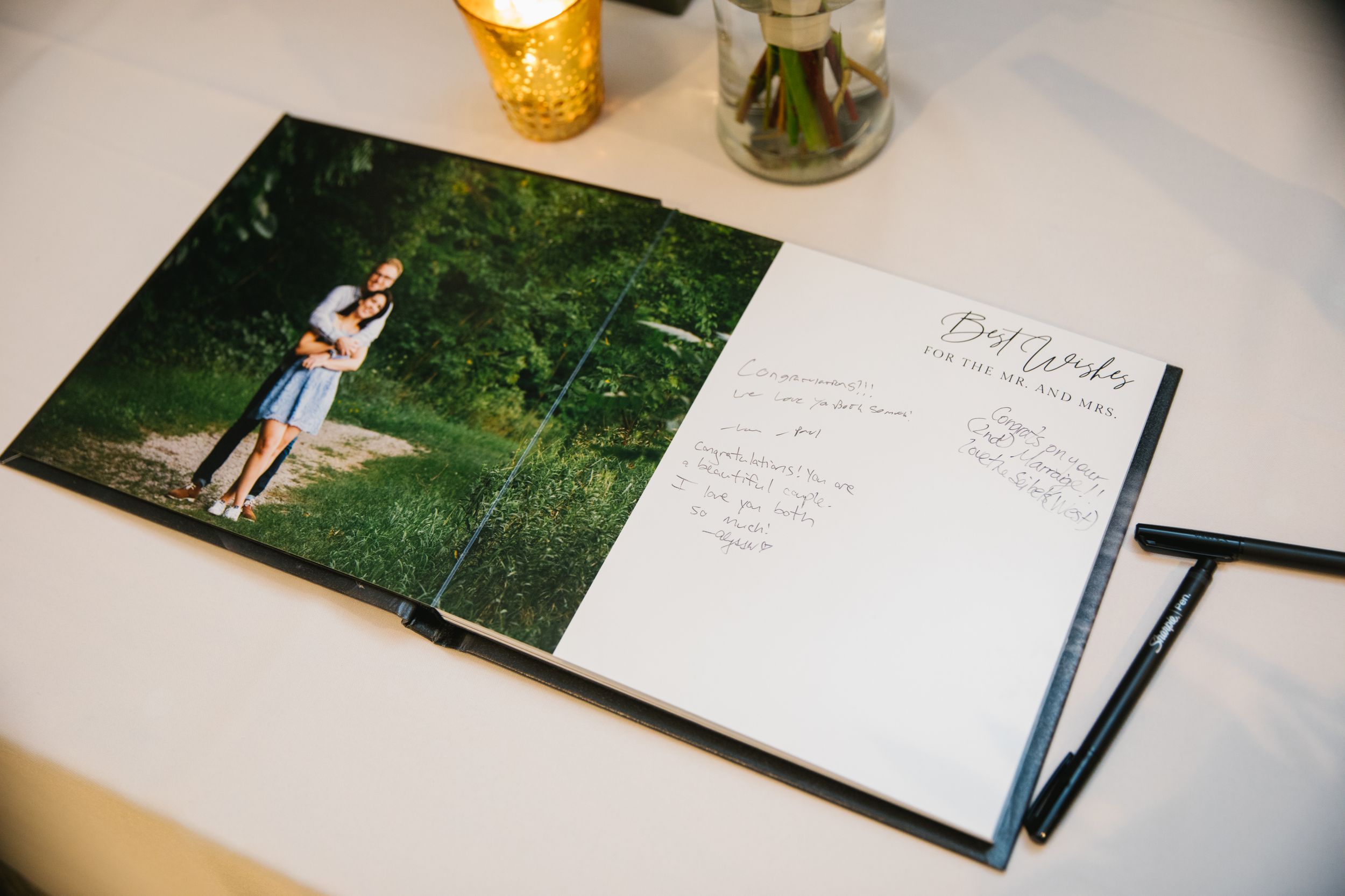 close up of guest signing book with engagement photo and congratulations