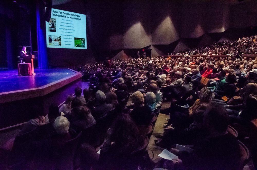 Picture of autistic celebrity Temple Grandin speaking on stage in front of a packed auditorium.