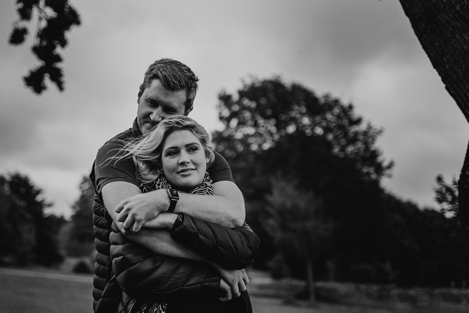 Black and white image of a couple sharing a moment and cuddle in a park. Katherine and her Camera engagement photoshoot.