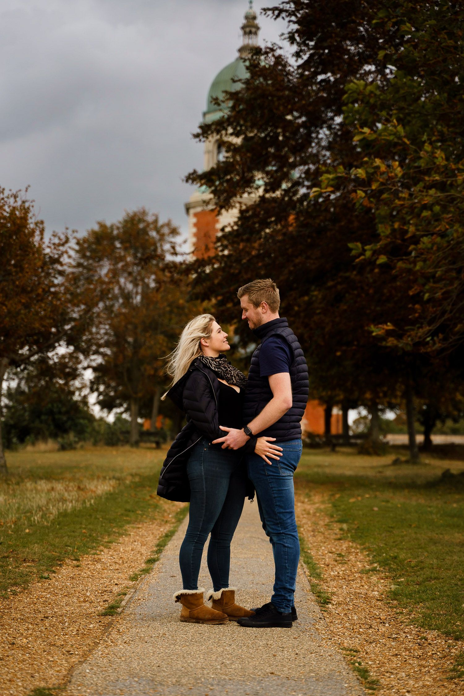 Couple stand and look at each other on a path in front of Netley Chapel. Katherine and her Camera engagement photoshoot.