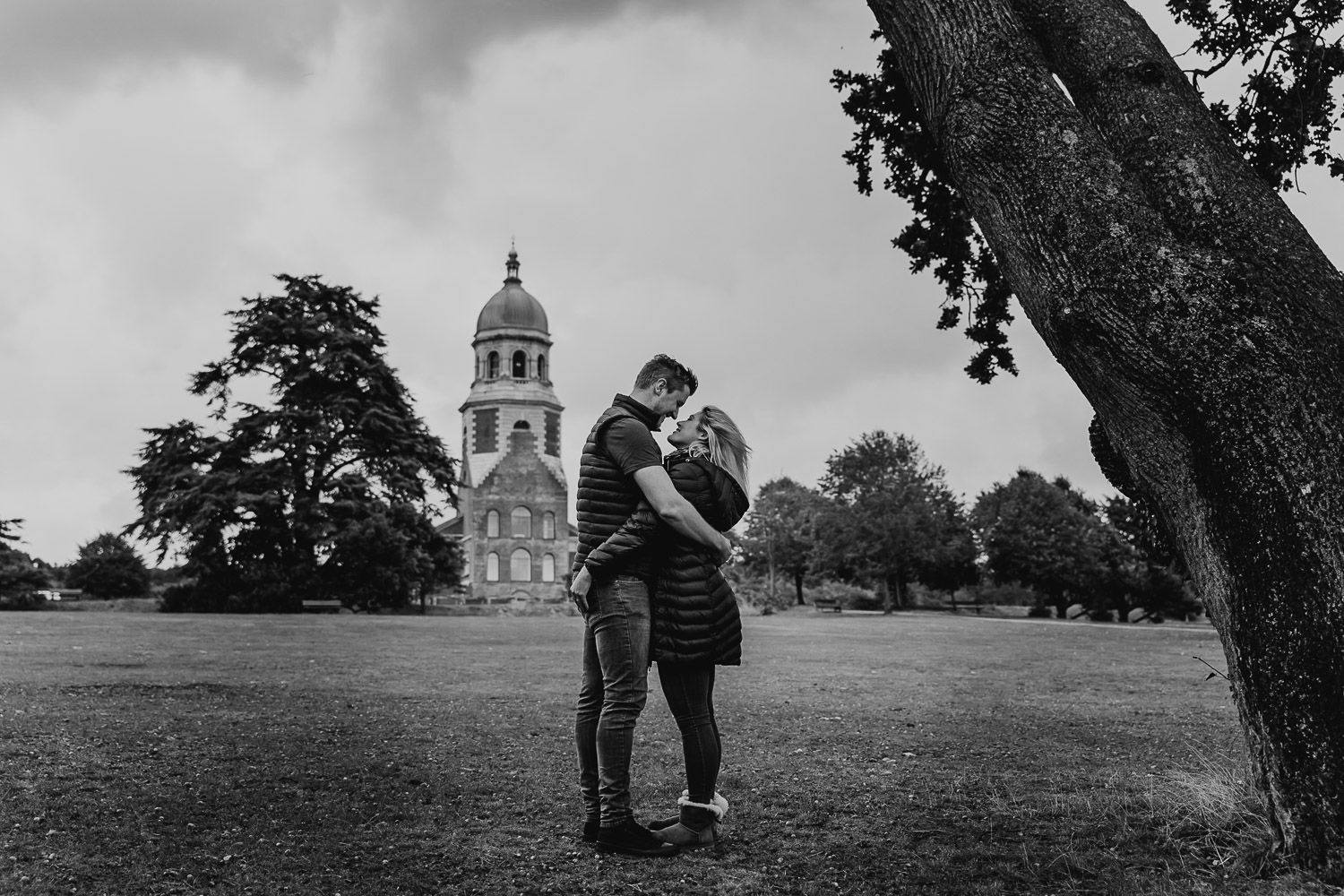 Black and white image of couple stood cuddling in front of Netley Chapel. Katherine and her Camera engagement photoshoot
