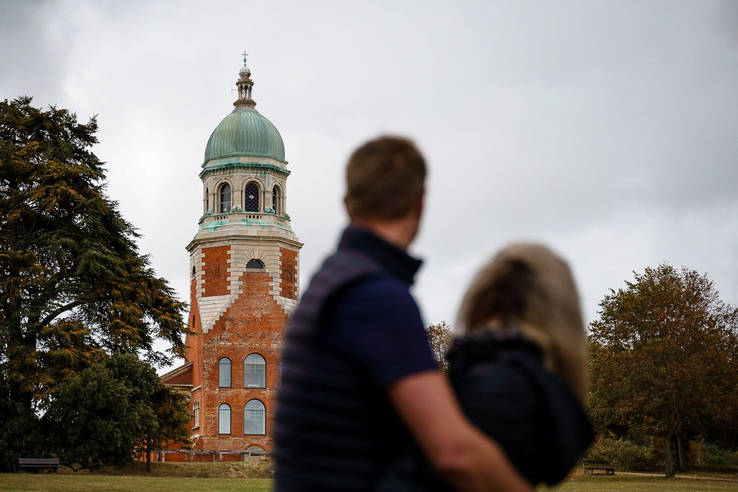Couple blurred in foreground look at Netley Chapel in the background. Katherine and her Camera engagement photoshoot.