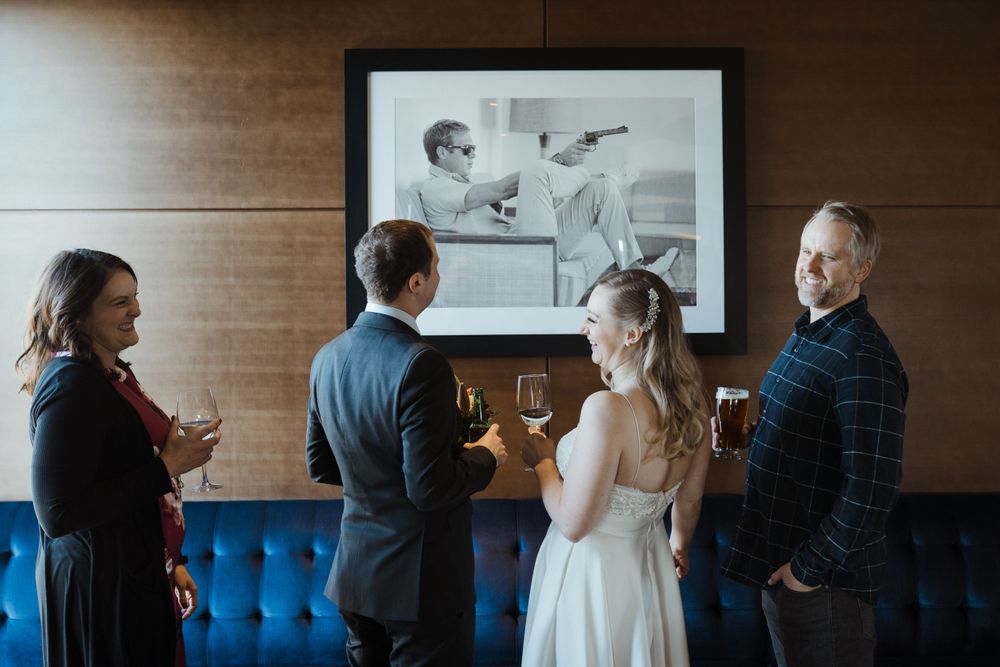 bride-groom-and-friends-talking-in-front-of-art-the-republic-on-grand-elopement-desmoines-iowa-raelyn-ramey-photography