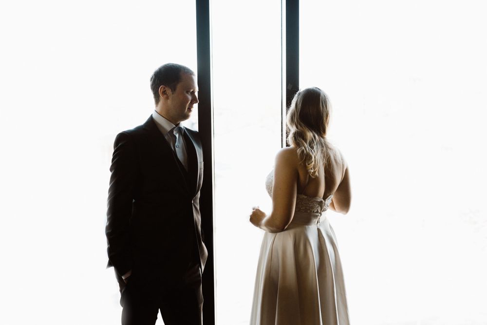 bride-groom-standing-in-front-of-windows-the-republic-on-grand-elopement-desmoines-iowa-raelyn-ramey-photography