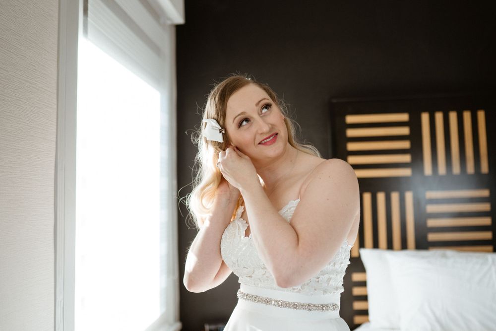 bride-putting-earings-in-getting-ready-savory-hotel-desmoines-iowa-raelyn-ramey-photography