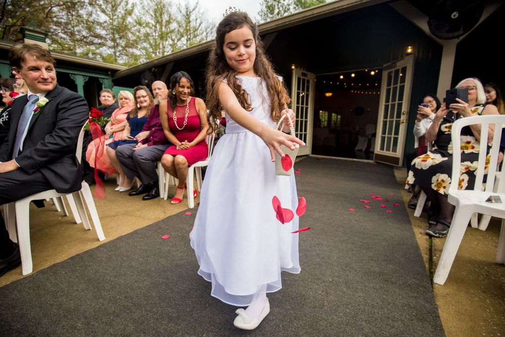 Flower girl spreads flowers on the aisle during a wedding ceremony at Winter Green Woods in Lexington, SC
