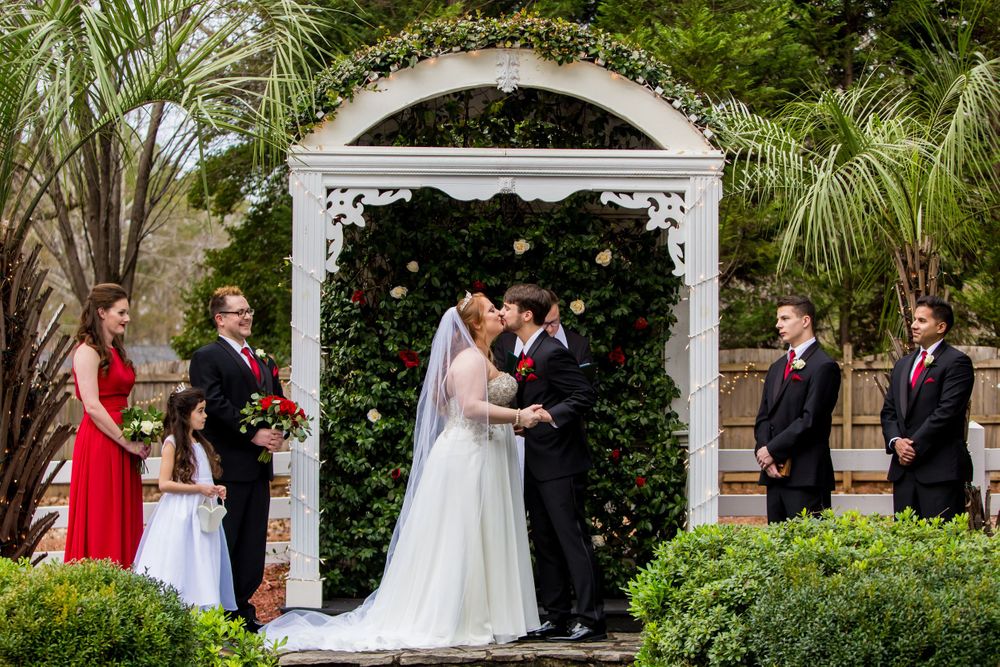 Bride and groom share their first kiss during a wedding ceremony at Winter Green Woods in Lexington, SC