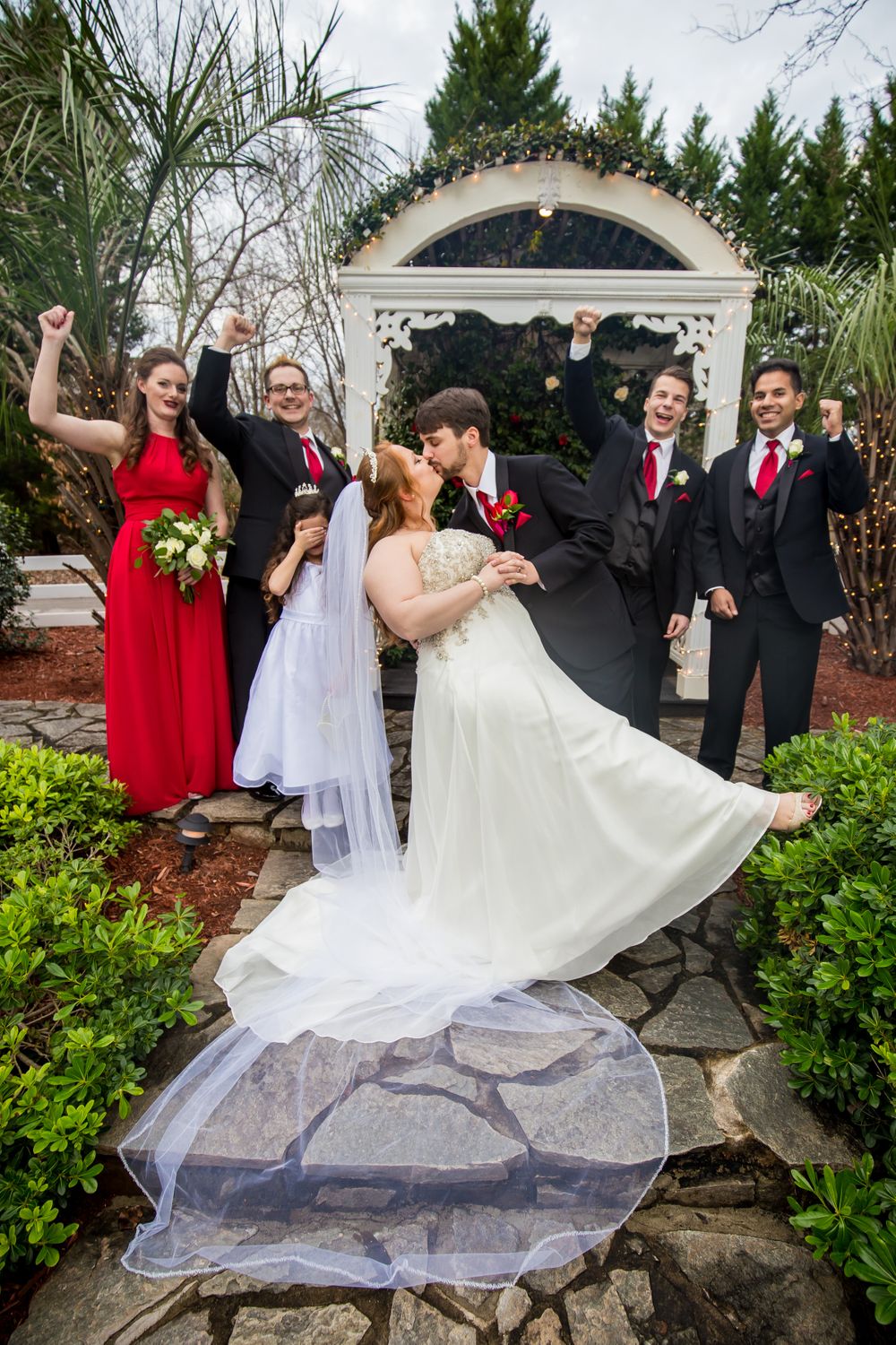 Bride and groom kiss and wedding party cheers during a portrait at Winter Green Woods in Lexington, SC