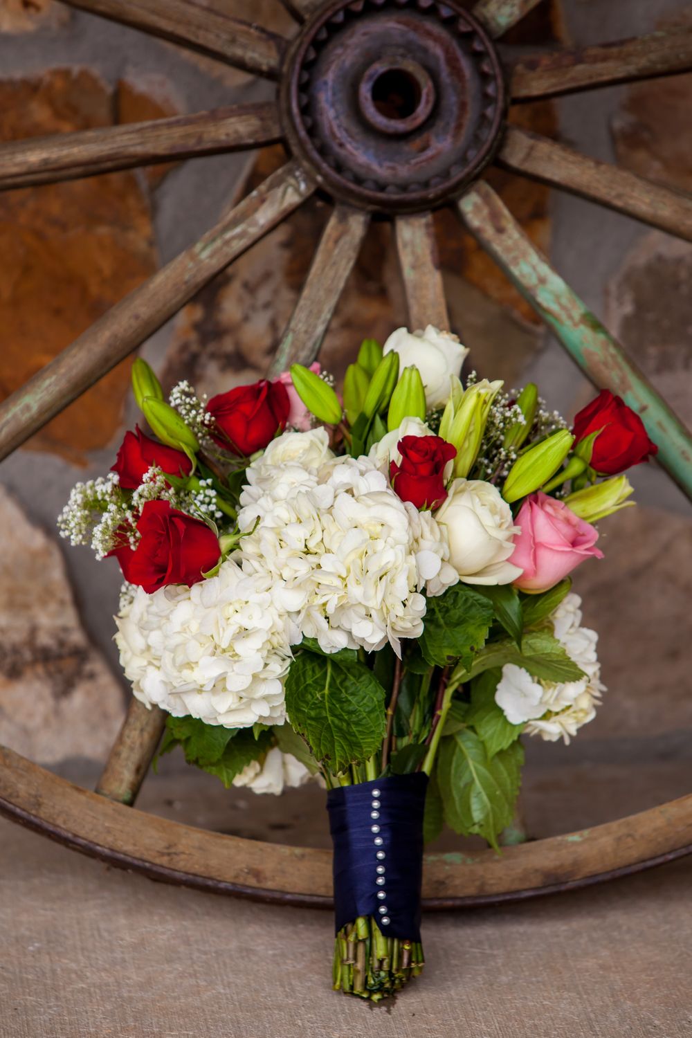 A bridal bouquet in front of a rusty wagon wheel at the Farm at Ridgeway in Ridgeway, SC